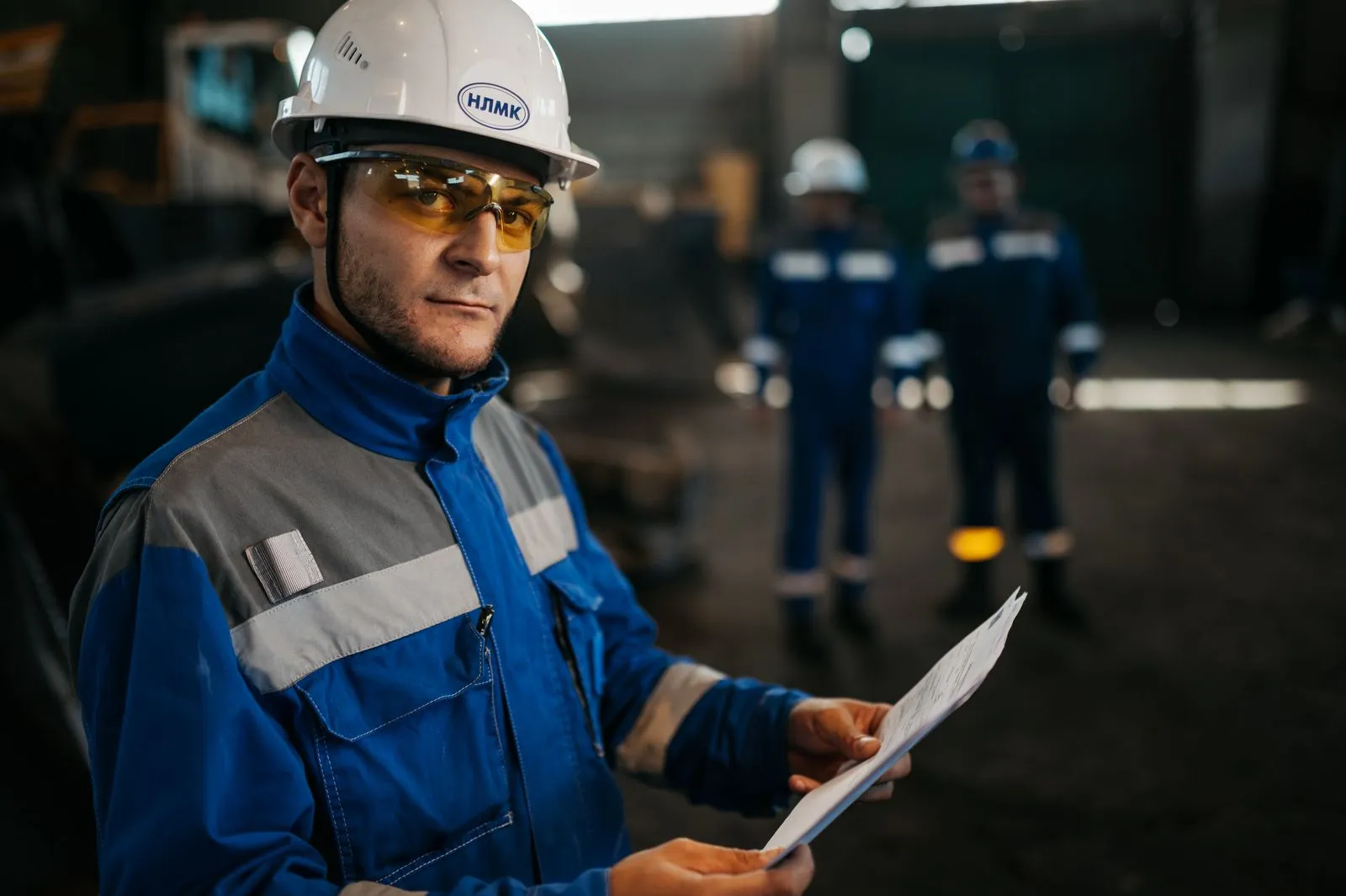 Industrial worker in protective gear reviewing documents in a factory setting